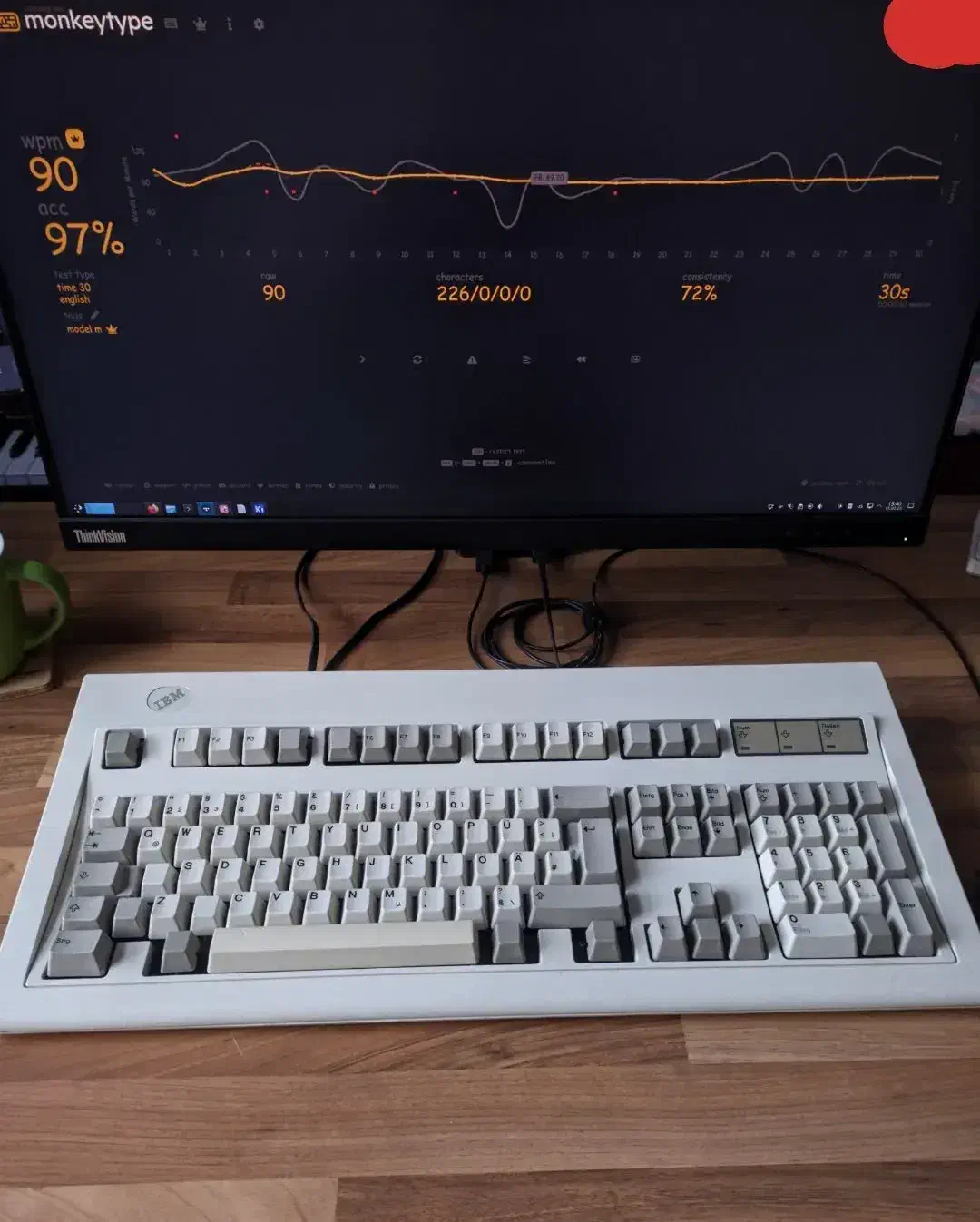 IBM Model M keyboard in front of a screen showing monkeytype at 90WPM.